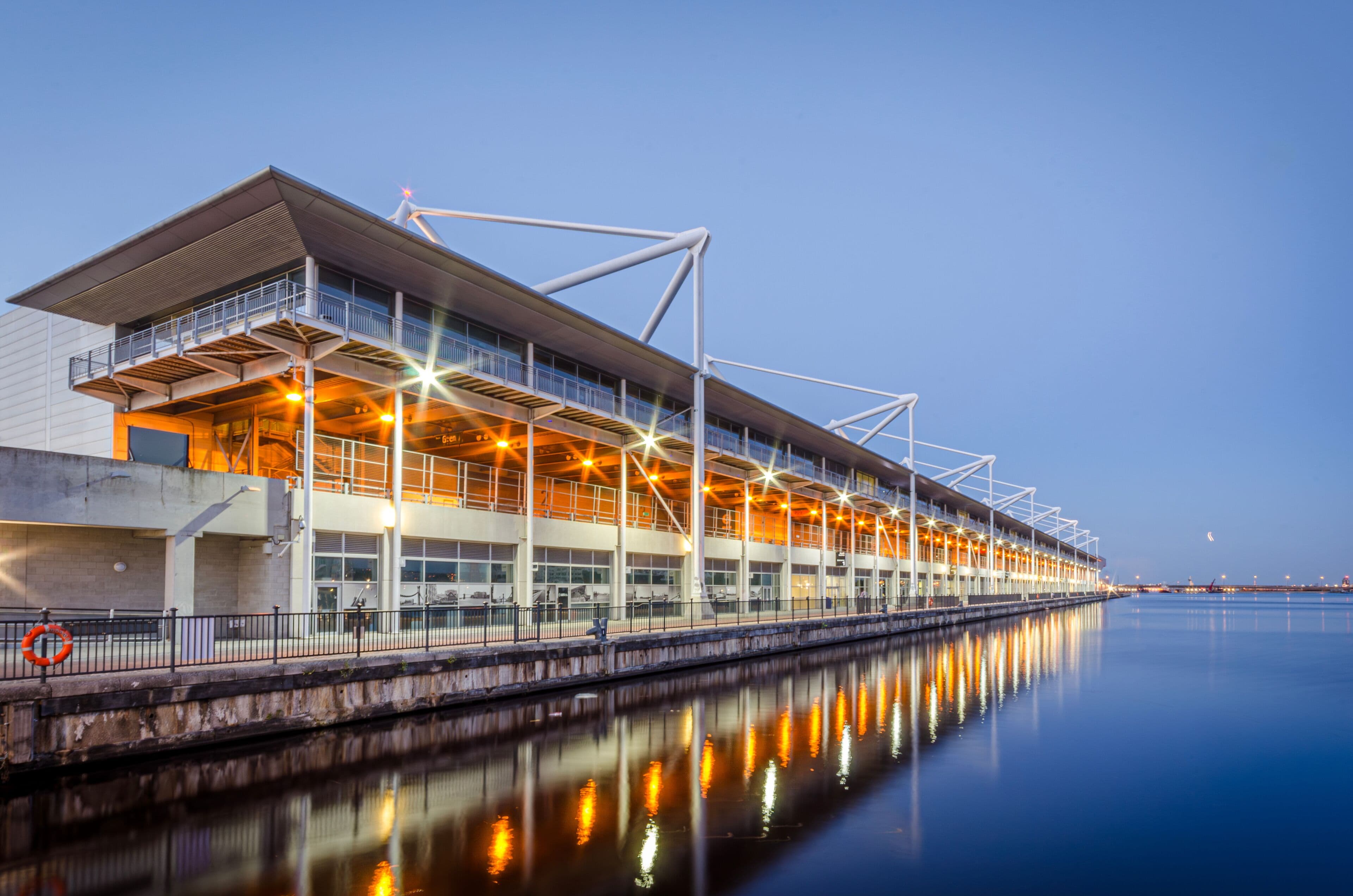 ExCeL London beside the dock at dusk, with lights reflected in the water.