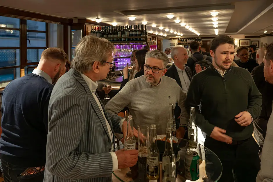 Attendees talking around a table at a busy networking event.